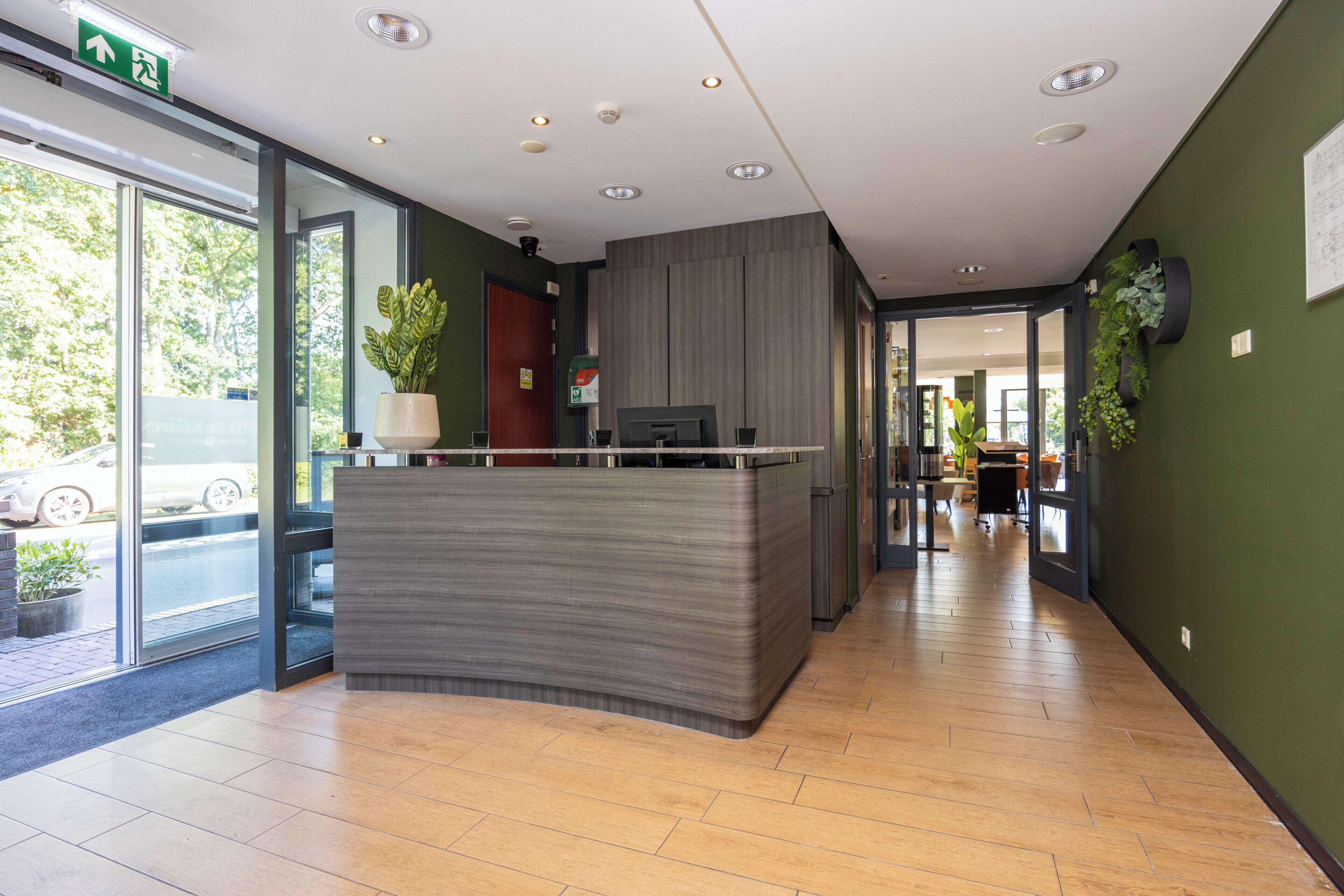 A reception area with a counter, a plant, and a door leading to another room.