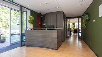A reception area with a counter, a plant, and a door leading to another room.