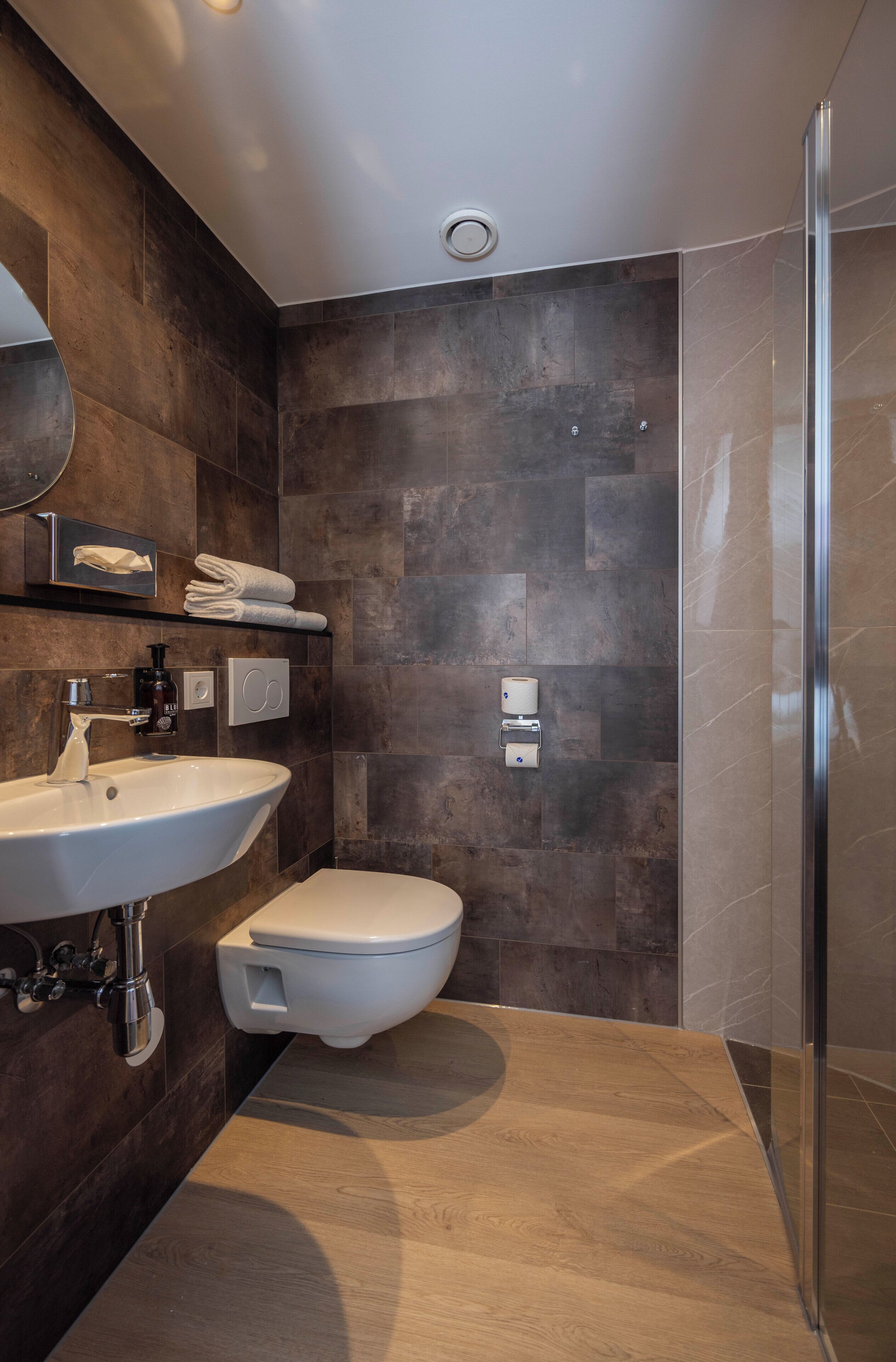 A modern bathroom with a large sink, toilet, and shower area.