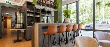 A bar area with stools, a bar counter, and a large window with a view of the street.