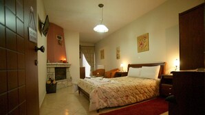 Een slaapkamer met een bed, een open haard, een nachtkastje en een rood vloerkleed.
