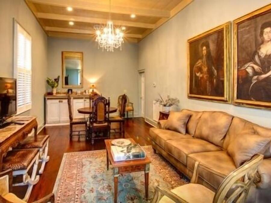 A living room with a sofa, a television, a dining table with chairs, and a chandelier.