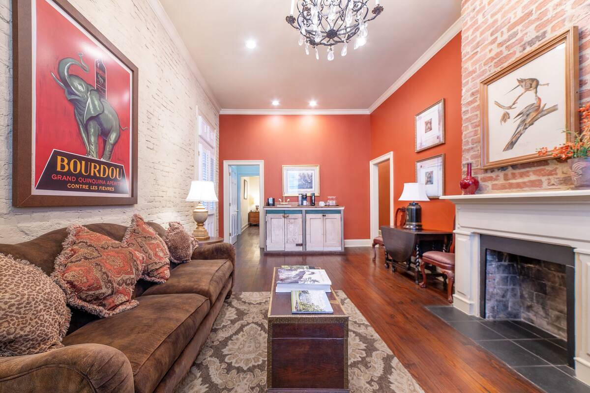 A living room with a brown sofa, a coffee table, a fireplace, and a kitchen in the background.