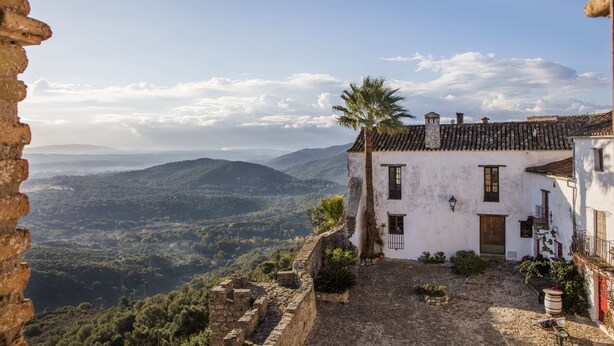 A white building with a tiled roof, a wooden door, and a small balcony with a railing. - TUGASA Castillo de Castellar (Castellar de la Frontera)