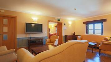 Habitación de hotel con televisión, asientos cómodos, chimenea y vistas al exterior.
