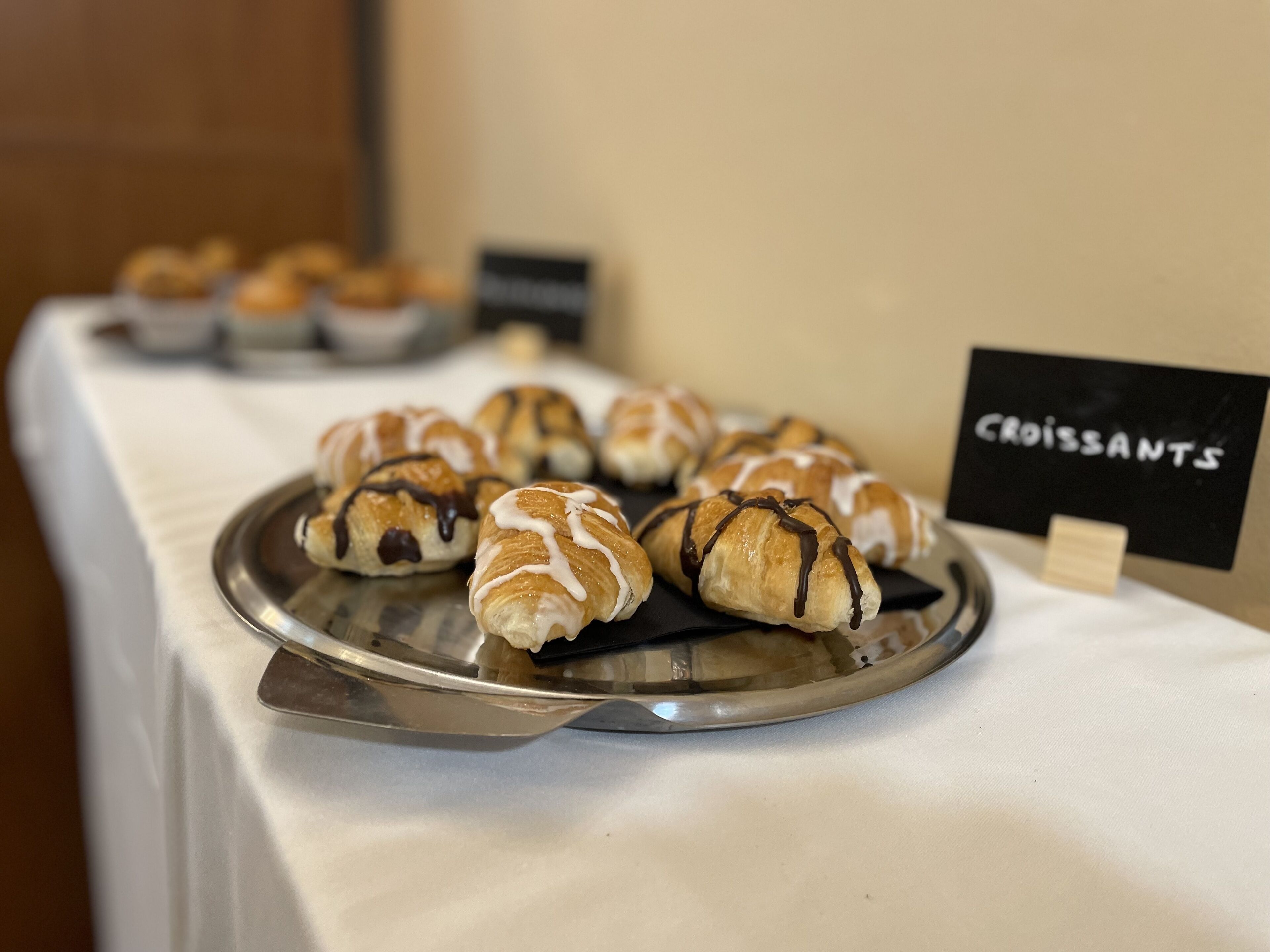 Una bandeja de croissants sobre una mesa con un letrero que dice 'Croissants'.