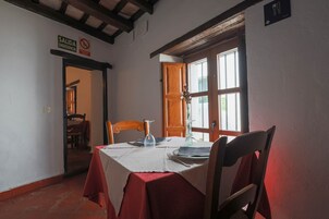 Comedor con una mesa dispuesta para dos, una puerta de madera y un cartel que indica zona para no fumadores.