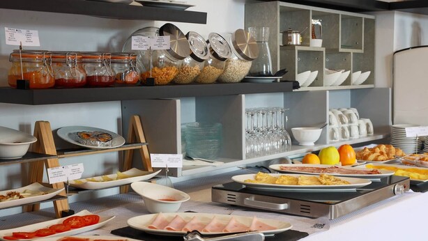 A buffet with various food items and condiments, including jars of sauces and bowls of sliced meats. - TUGASA El Almendral (Setenil de las Bodegas)