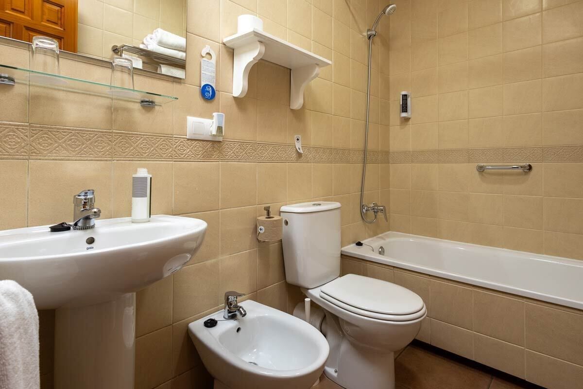 A bathroom with a sink, bidet, toilet, and bathtub.