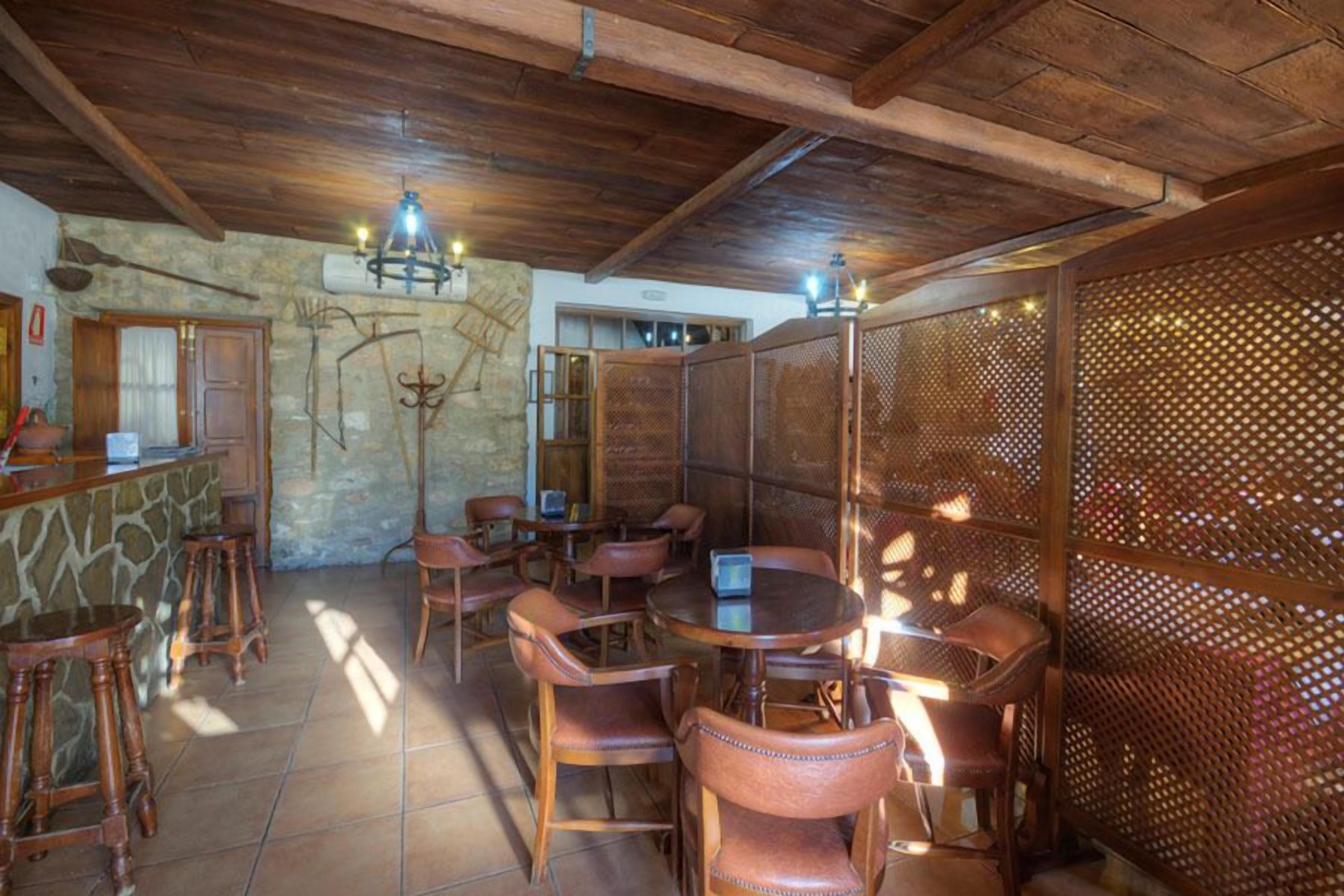 Un comedor rústico con mobiliario de madera, paredes de piedra y un techo alto.