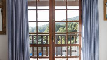 Una habitación con cama, vistas a través de un ventanal y cortinas.