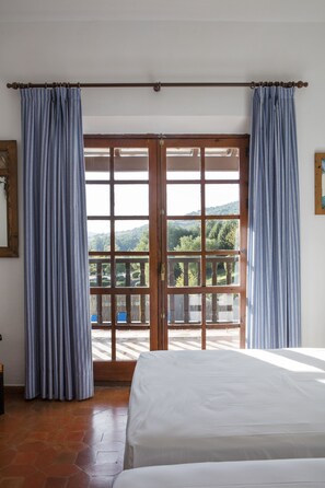A room with a bed, a view through a glass door, and curtains.