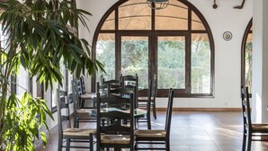 Un comedor con una mesa dispuesta para cuatro personas, rodeada de sillas, bajo un techo de madera con una araña.