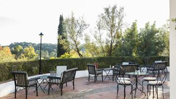 Enjoy dining or socializing in a serene outdoor space surrounded by trees and hedges.