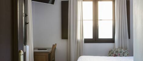 Ein Hotelzimmer mit Bett, Schreibtisch und Wandfernseher.