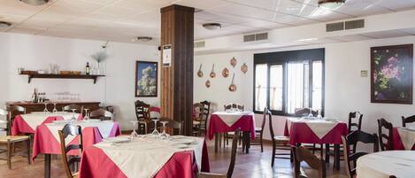 Ein Restaurant mit mehreren Tischen, bedeckt mit rot-weißen Tischdecken, Holzkästen und einem gefliesten Boden.