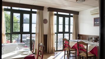A dining area with tables set for a meal, large windows, and a view of the outside.