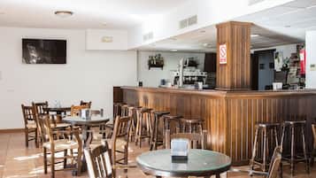 Un restaurante con muebles de madera, una zona de bar y un televisor de pantalla plana en la pared.