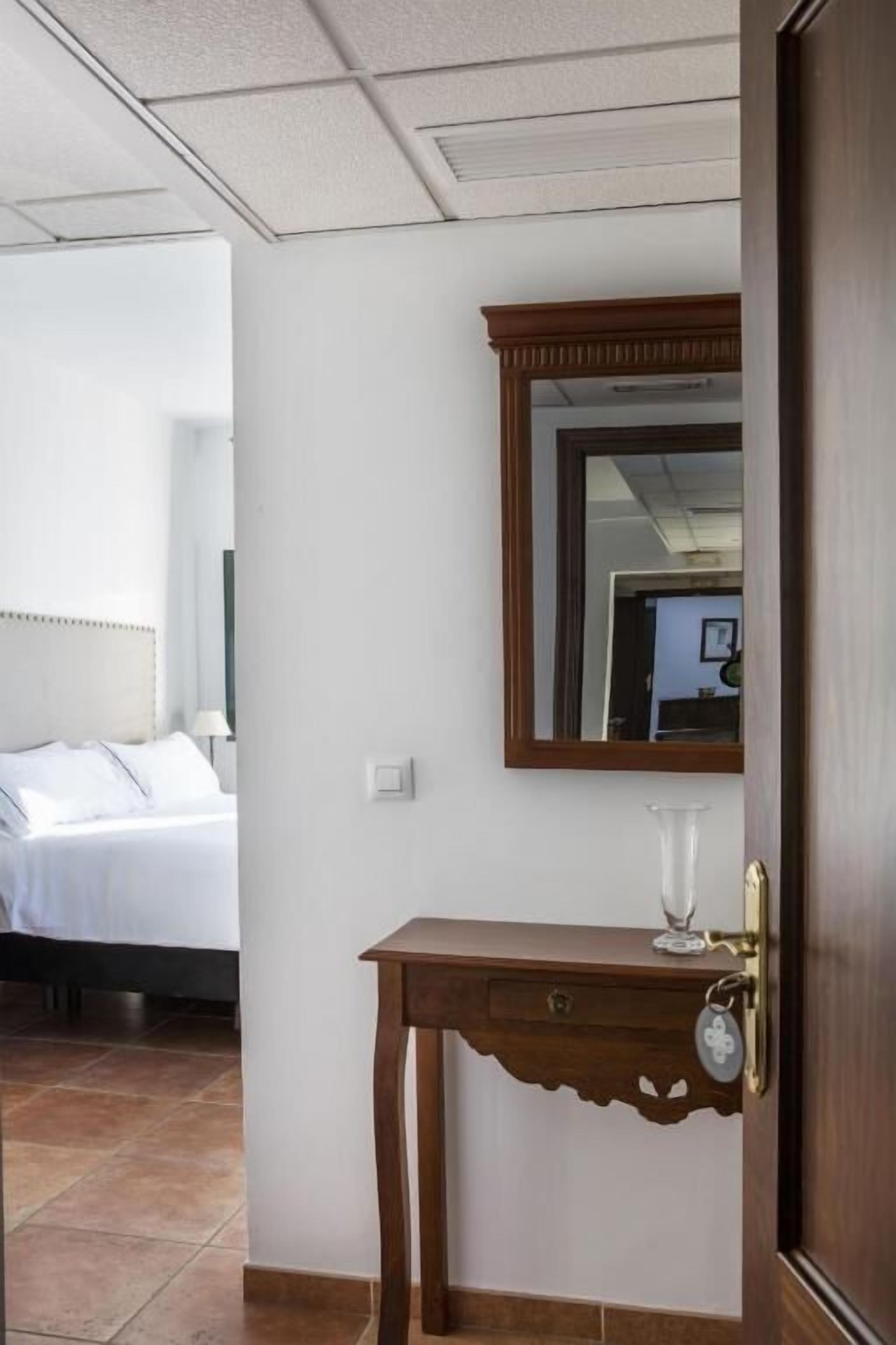 Una habitación de hotel con una cama, una mesita de noche con un vaso y un espejo en la pared.