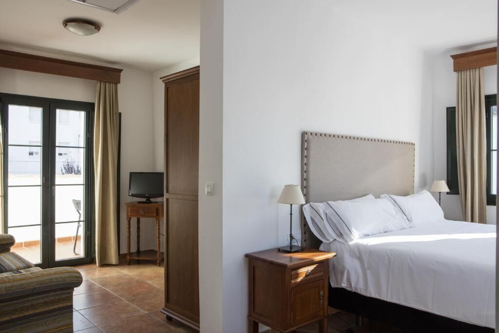 Una habitación de hotel con una cama, televisor, escritorio y silla.