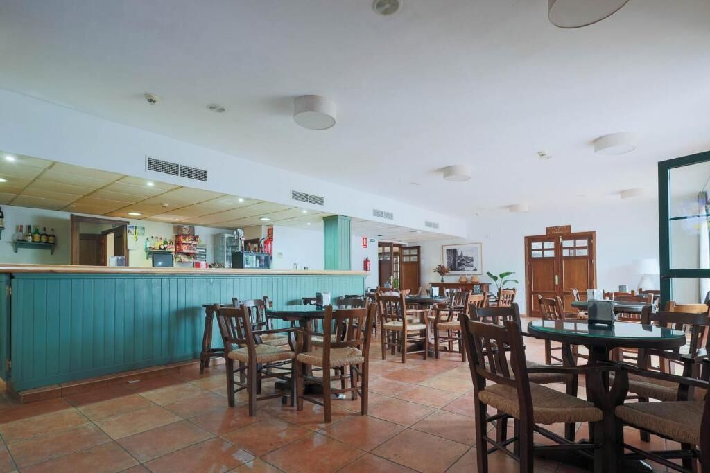 A restaurant with a counter and multiple tables and chairs.