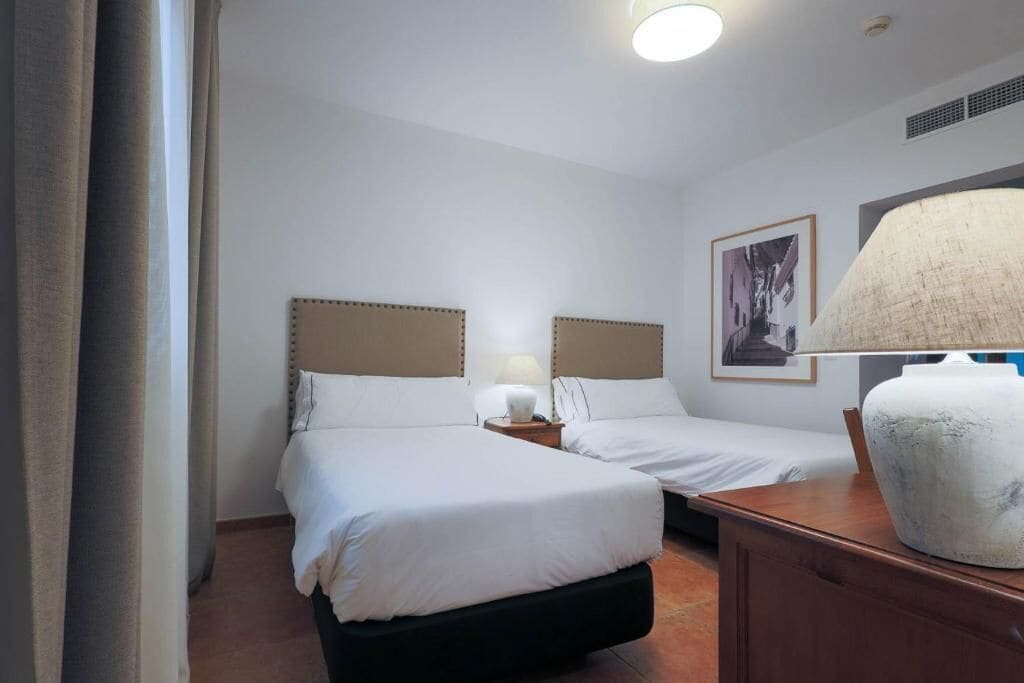 Een hotelkamer met twee bedden, een nachtkastje, een lamp en een grote vaas.