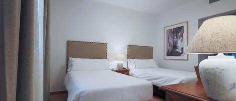 Een hotelkamer met twee bedden, een nachtkastje, een lamp en een grote vaas.