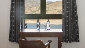 Um quarto com uma janela grande, uma escrivaninha de madeira e uma cadeira.