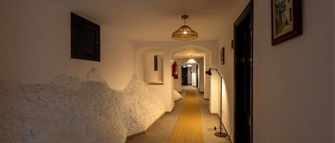 Un pasillo con pared texturizada, un candelabro colgante y un cuadro en la pared.