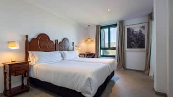 A hotel room with a large bed, bedside tables, a window with curtains, and a framed picture on the wall.