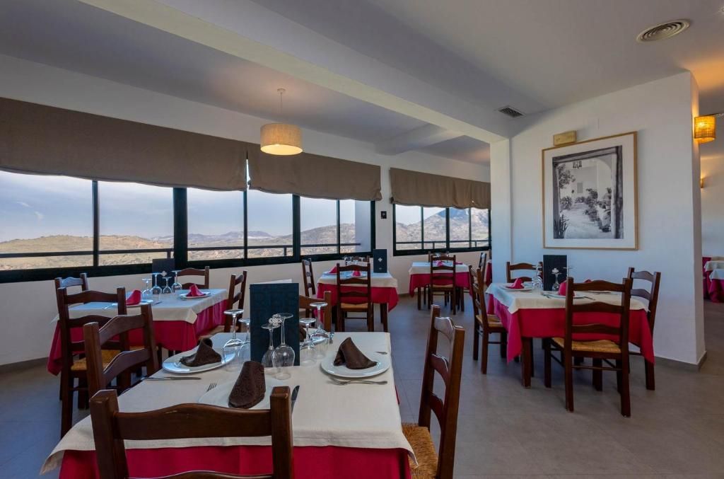 A restaurant with tables set for dining, large windows offering a view, and a framed picture on the wall.