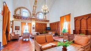 A spacious room with wooden furniture, a chandelier, and large windows with curtains. - TUGASA Convento San Francisco (Vejer de la Frontera)