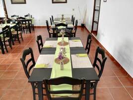 A dining area with multiple tables set for service, each with a green tablecloth, black chairs, and centerpieces.