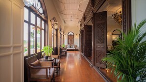 A hallway with wooden flooring, wicker furniture, and large windows. - Praya Palazzo (Bangkok)
