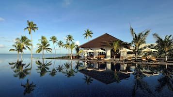 Alberca al aire libre, sombrillas en la alberca y camastros