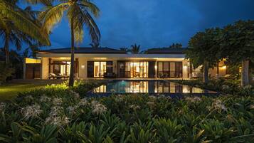 A modern house with a swimming pool surrounded by tropical plants.