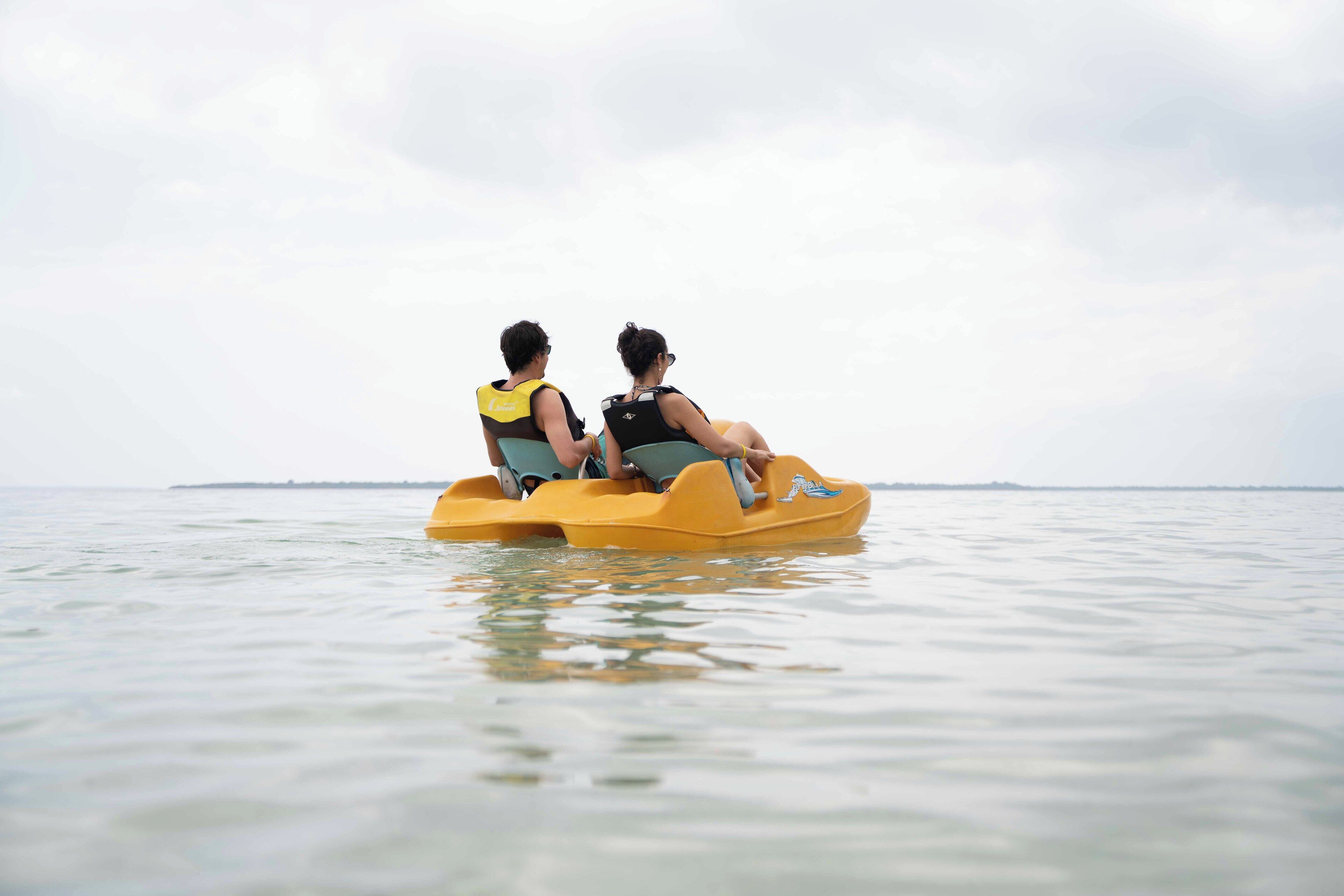 Two people on a yellow raft in calm water.