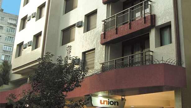 A multi-story building with balconies, a visible entrance, and a sign that reads "union". - Collins Trade Hotel (Porto Alegre)