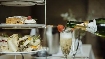 A multi-tiered dessert stand with various pastries and a bottle of champagne being poured into a glass.