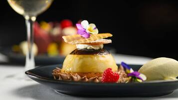 A dessert with a caramelized top, a wafer, and a flower on a plate.