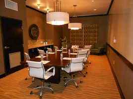 A conference room with a large table, white chairs, and overhead lighting.