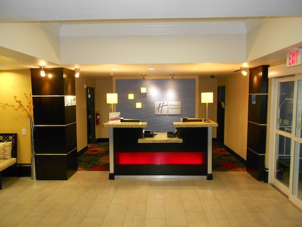 A reception desk with a Holiday Inn Express sign, a fire extinguisher, and a red illuminated panel.