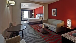 A hotel room with a bed, a sofa, a small table, a lamp, and a view of the outside. - Holiday Inn Express & Suites Wichita Northwest by IHG (Maize)