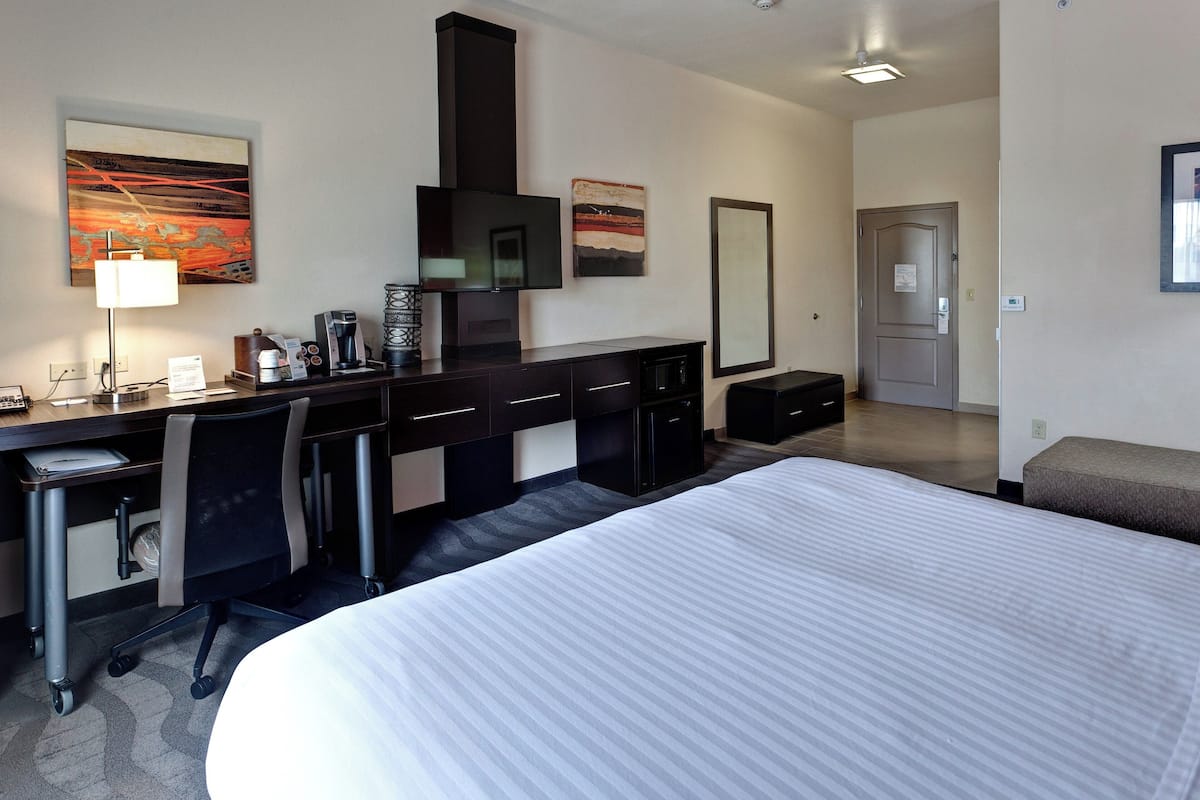 Une chambre d’hôtel avec un grand lit, un bureau avec un ordinateur, une machine à café et une cheminée.