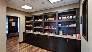 A hallway with a snack bar featuring shelves stocked with various food items and beverages. - Holiday Inn Express & Suites Wichita Northwest by IHG (Maize)