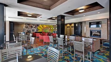 A spacious lobby with multiple seating areas, including a central red sofa and various tables and chairs.
