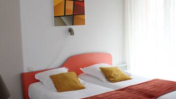A hotel room with a bed, a desk, and a painting on the wall.