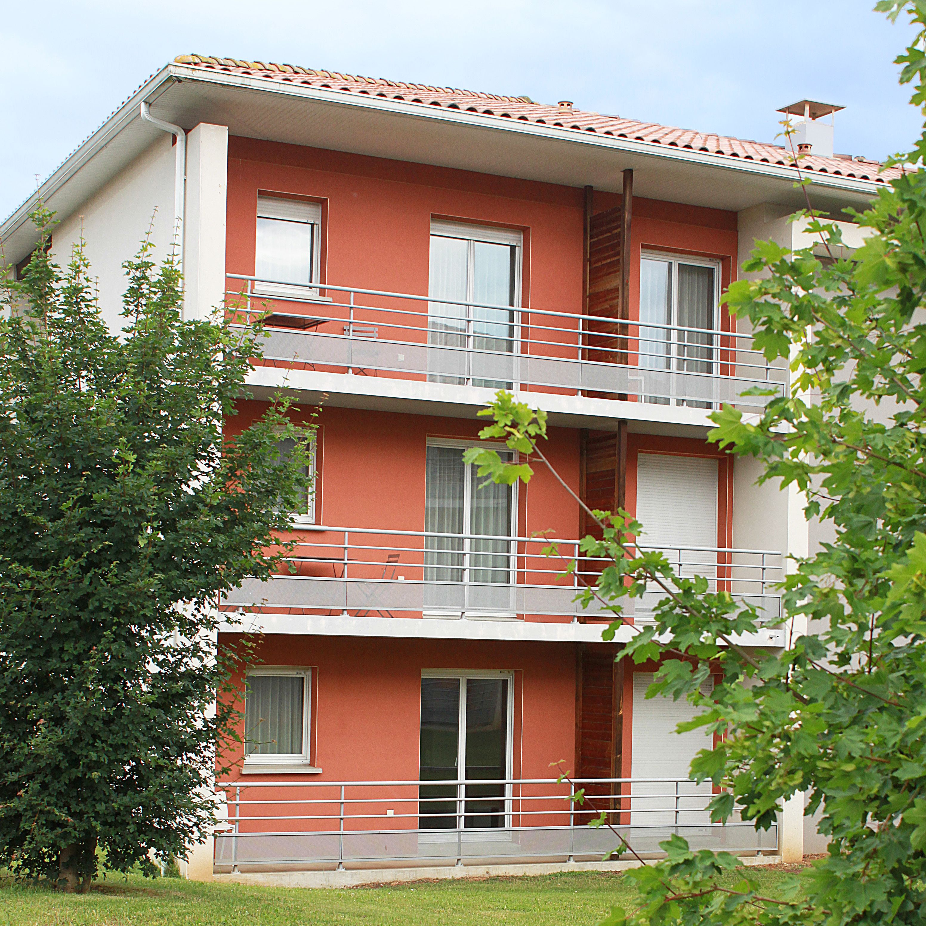 Un immeuble à plusieurs étages, doté de balcons, de fenêtres et d’une façade rouge.