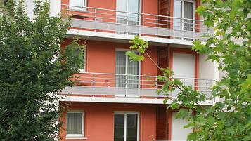 Un immeuble à plusieurs étages, doté de balcons, de fenêtres et d’une façade rouge.