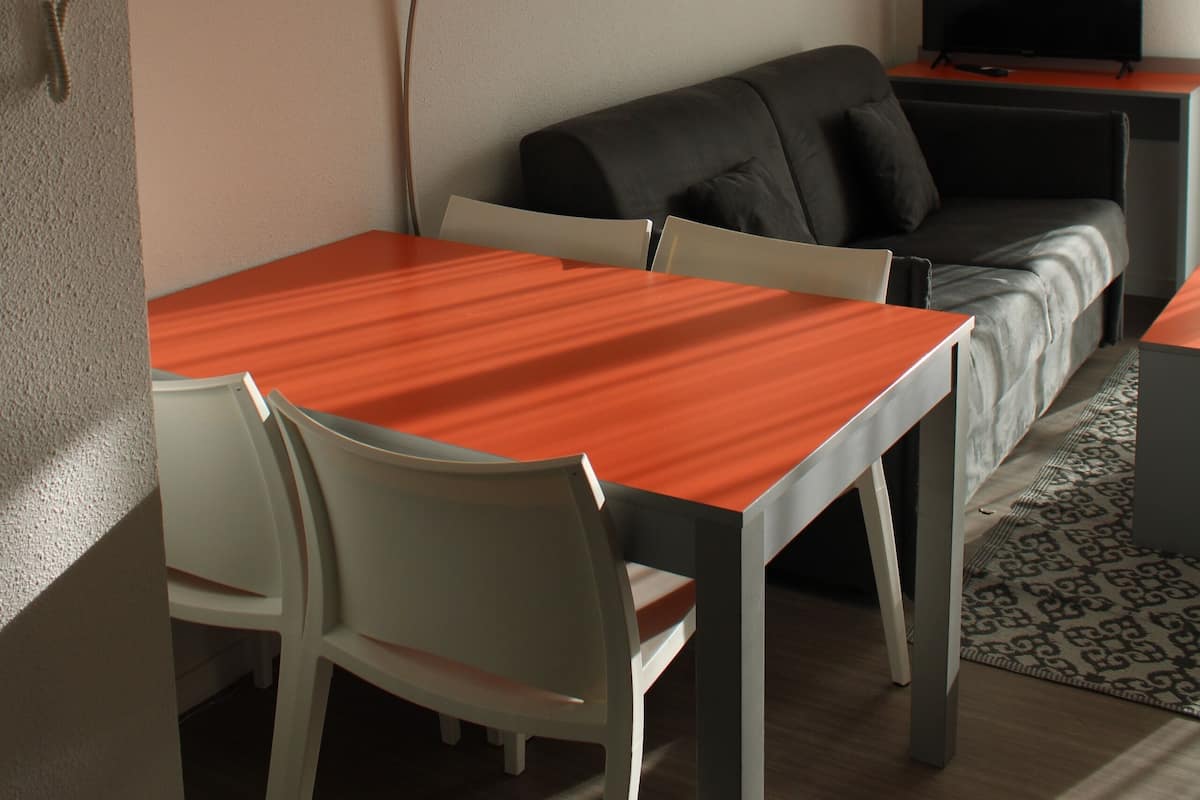 Een moderne woonkamer met een bank, een televisie, een eettafel en stoelen.